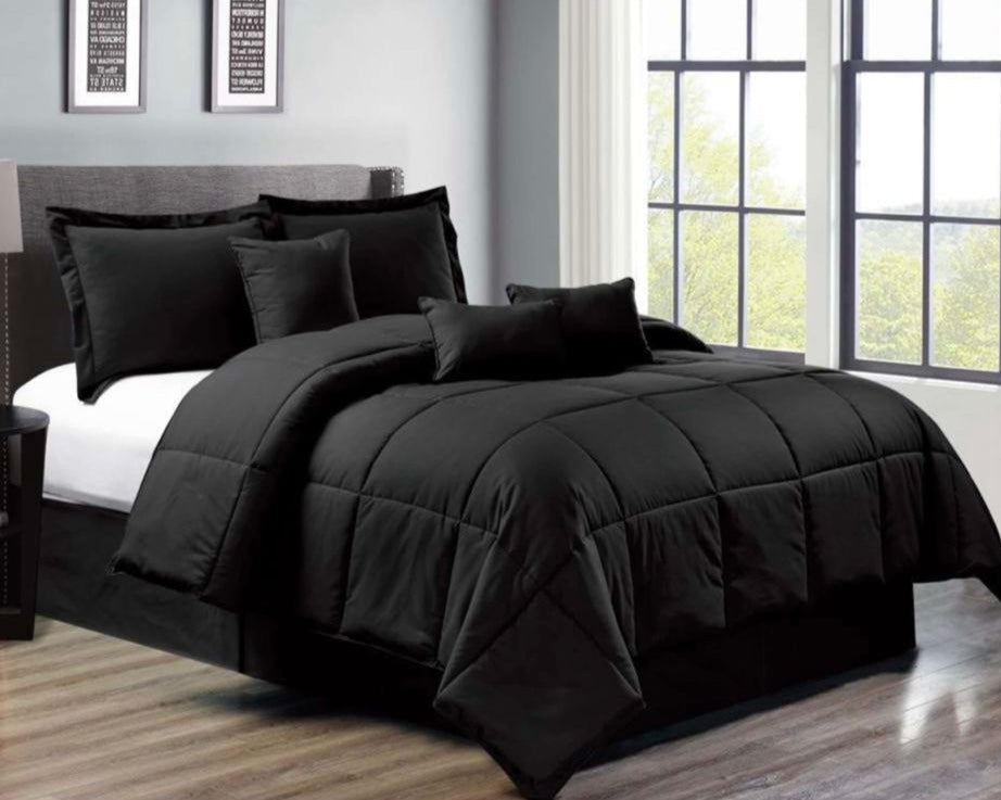Black comforter set on a bed in a room with large windows.