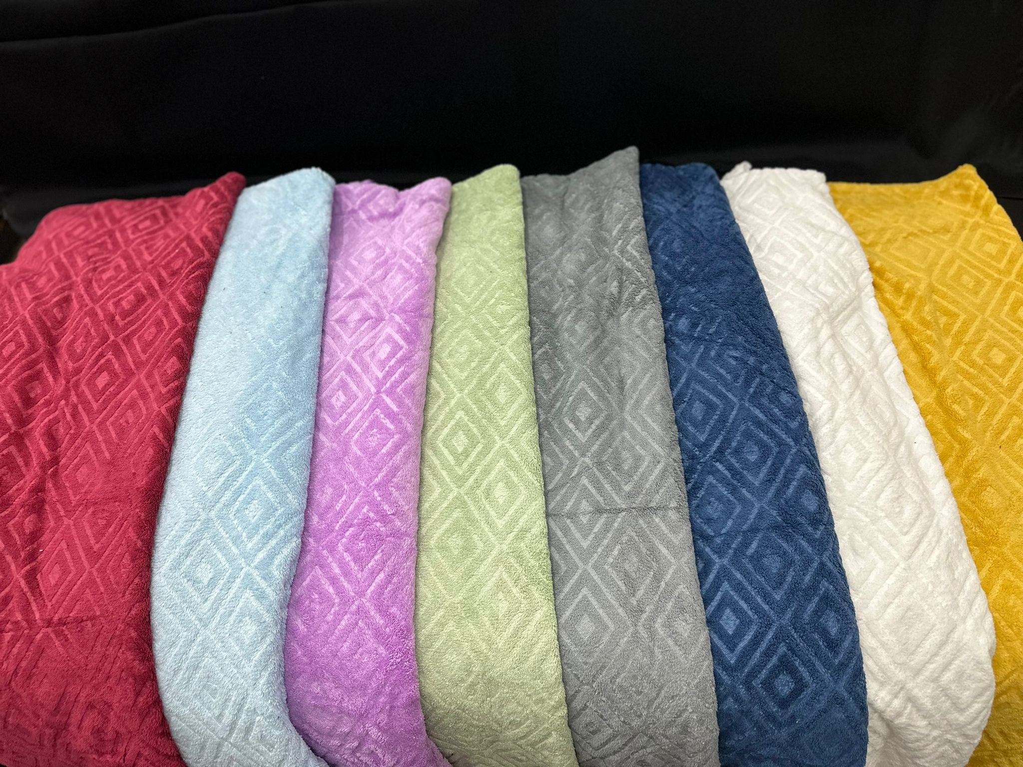Row of textured fabric samples in various colors on a black background