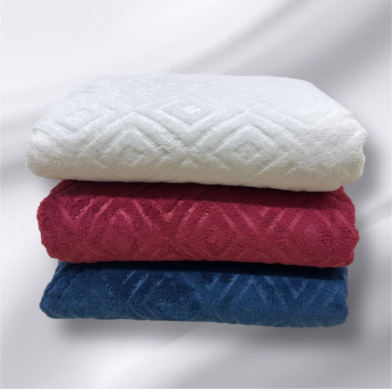 Stack of three folded towels in white, red, and blue on a light gray background