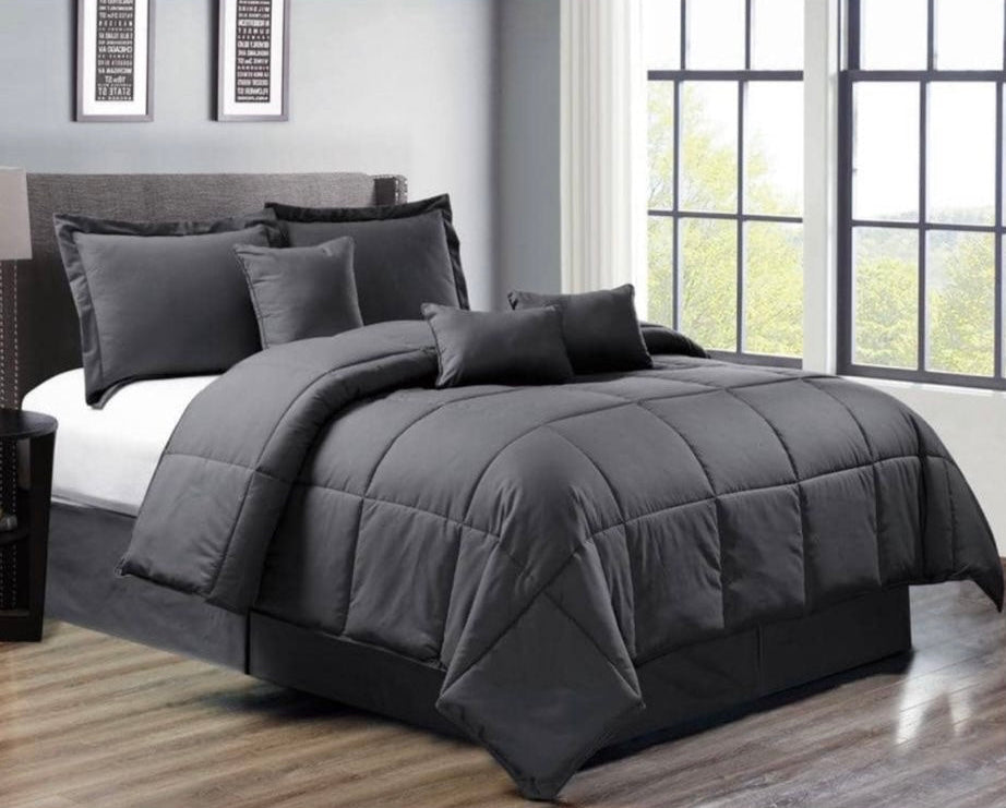 Gray bedding set on a bed in a room with large windows.
