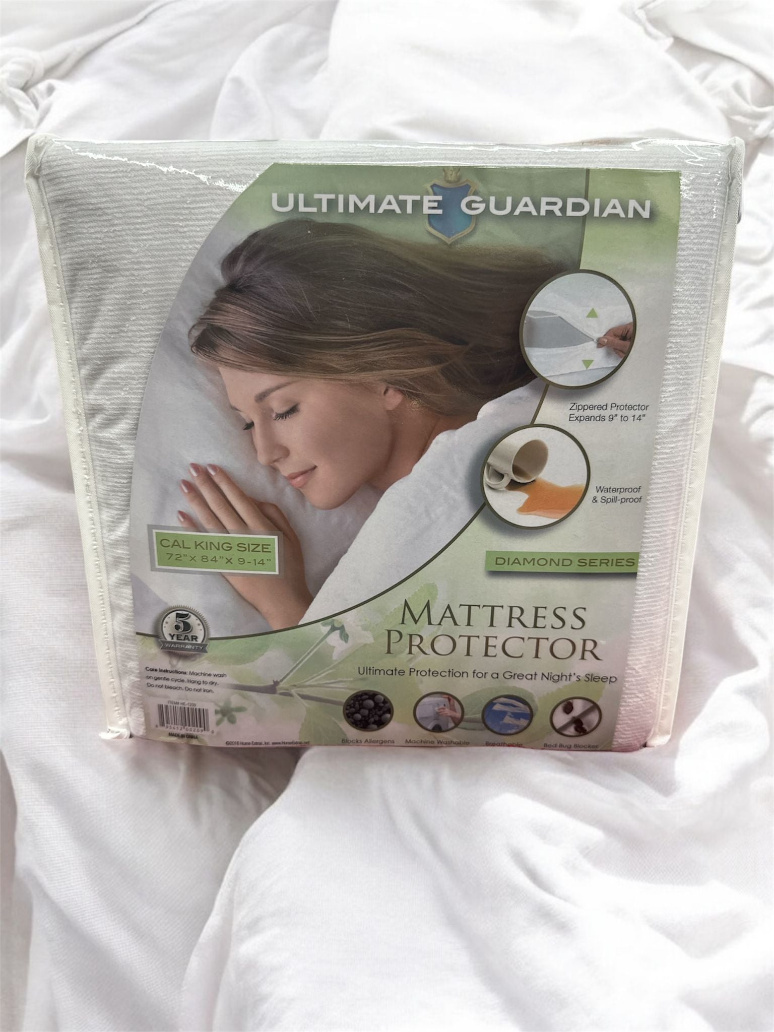 Packaged mattress protector with a woman's face on the label, set against a white mattress background.
