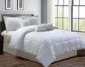 White comforter set on a bed in a room with large windows.